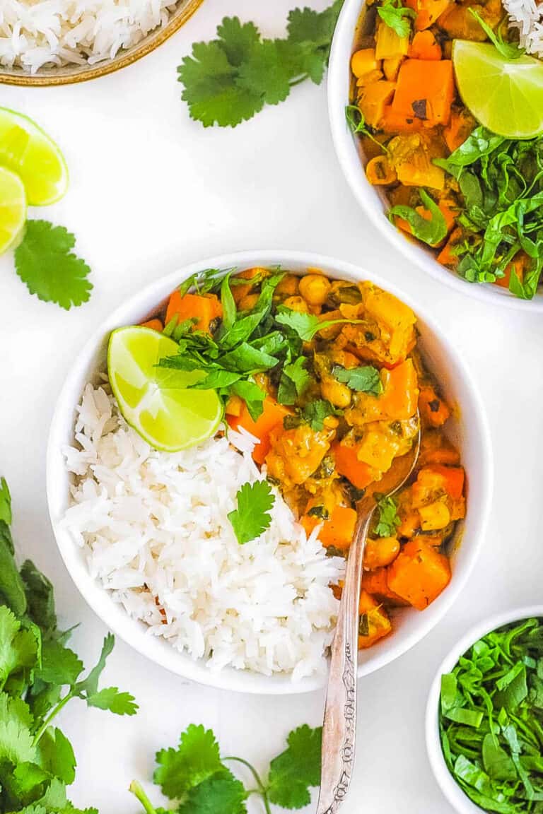 Sweet potato chickpea curry in a white bowl served with rice.