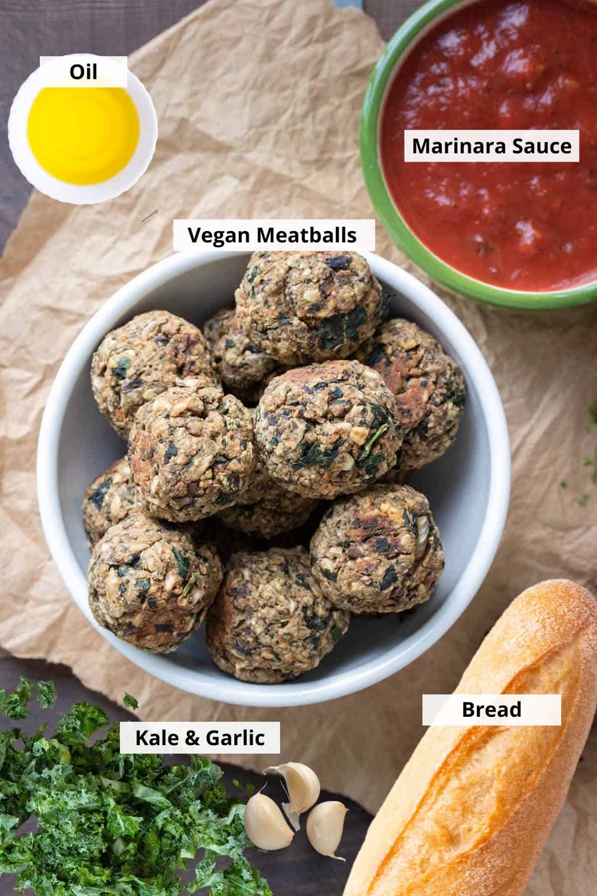 White bowl with vegan meatballs next to a bowl of marinara, garlic and kale.