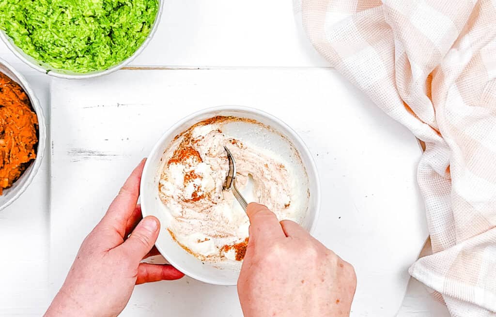 Greek yogurt mixed with taco seasoning in a mixing bowl.