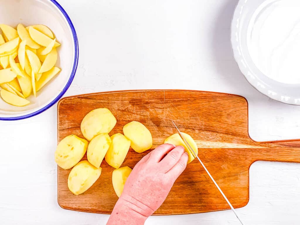 Apples being sliced on a wooden cutting board.