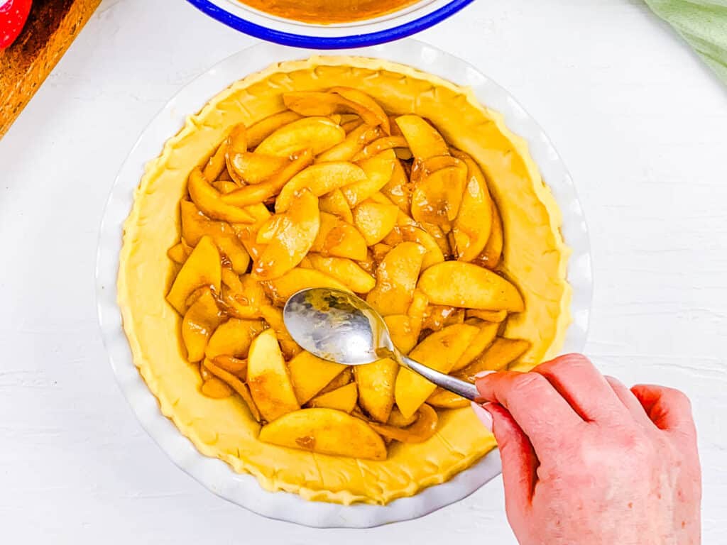 Apple pie filling added to pie crust in a baking dish.