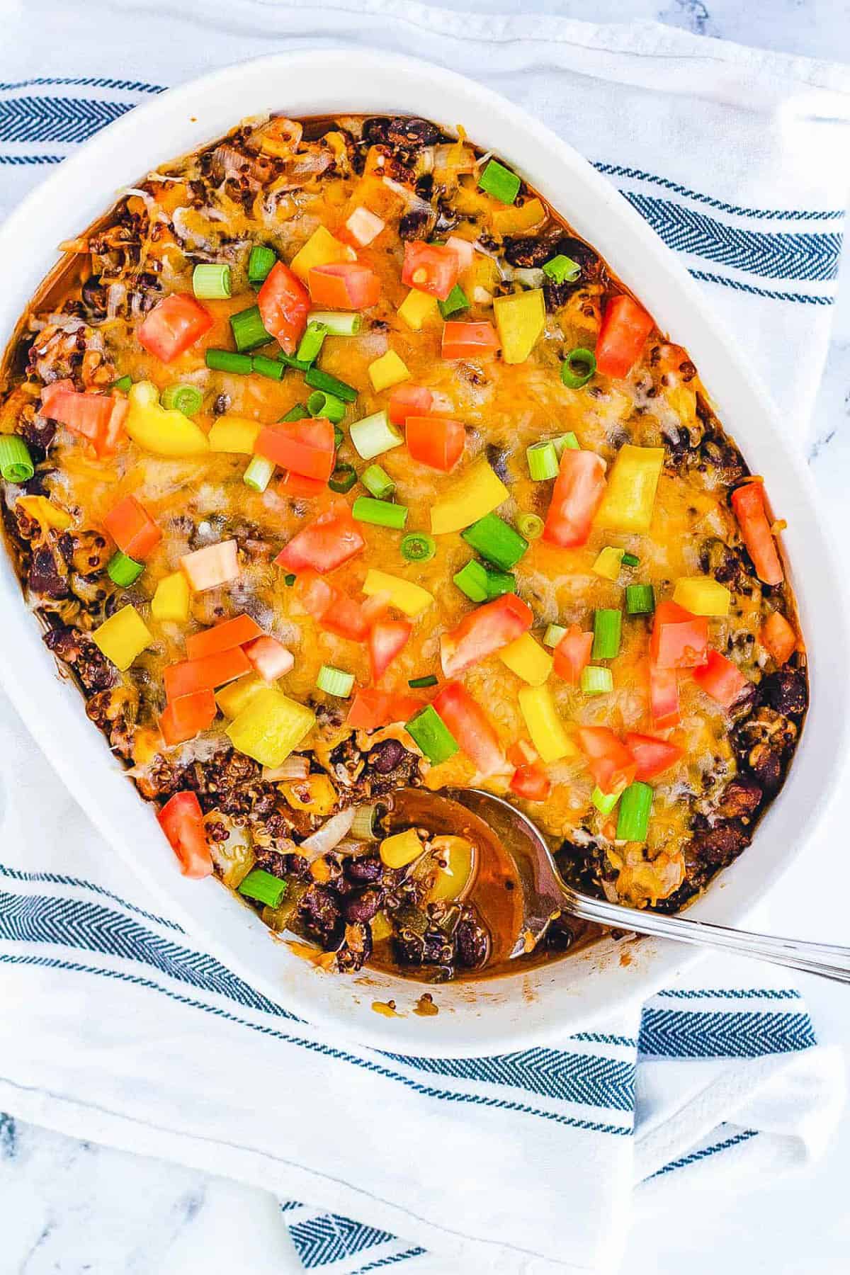 Overhead shot of a white casserole dish of quinoa casserole with a spoon.