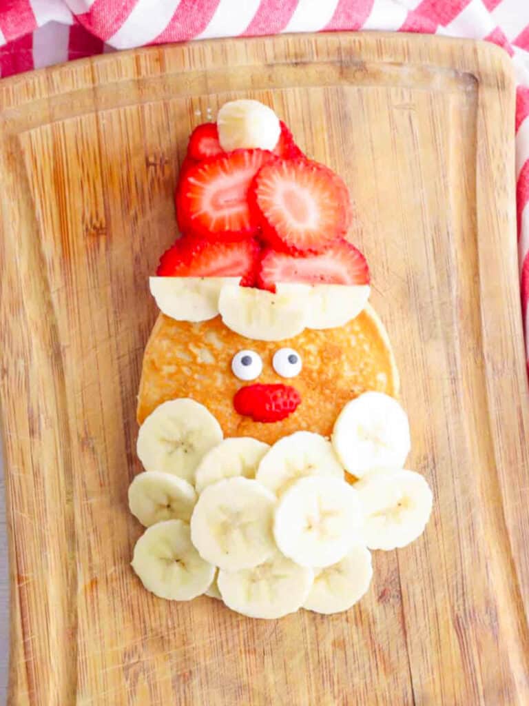 Overhead shot of a santa pancake on a wooden cutting board.