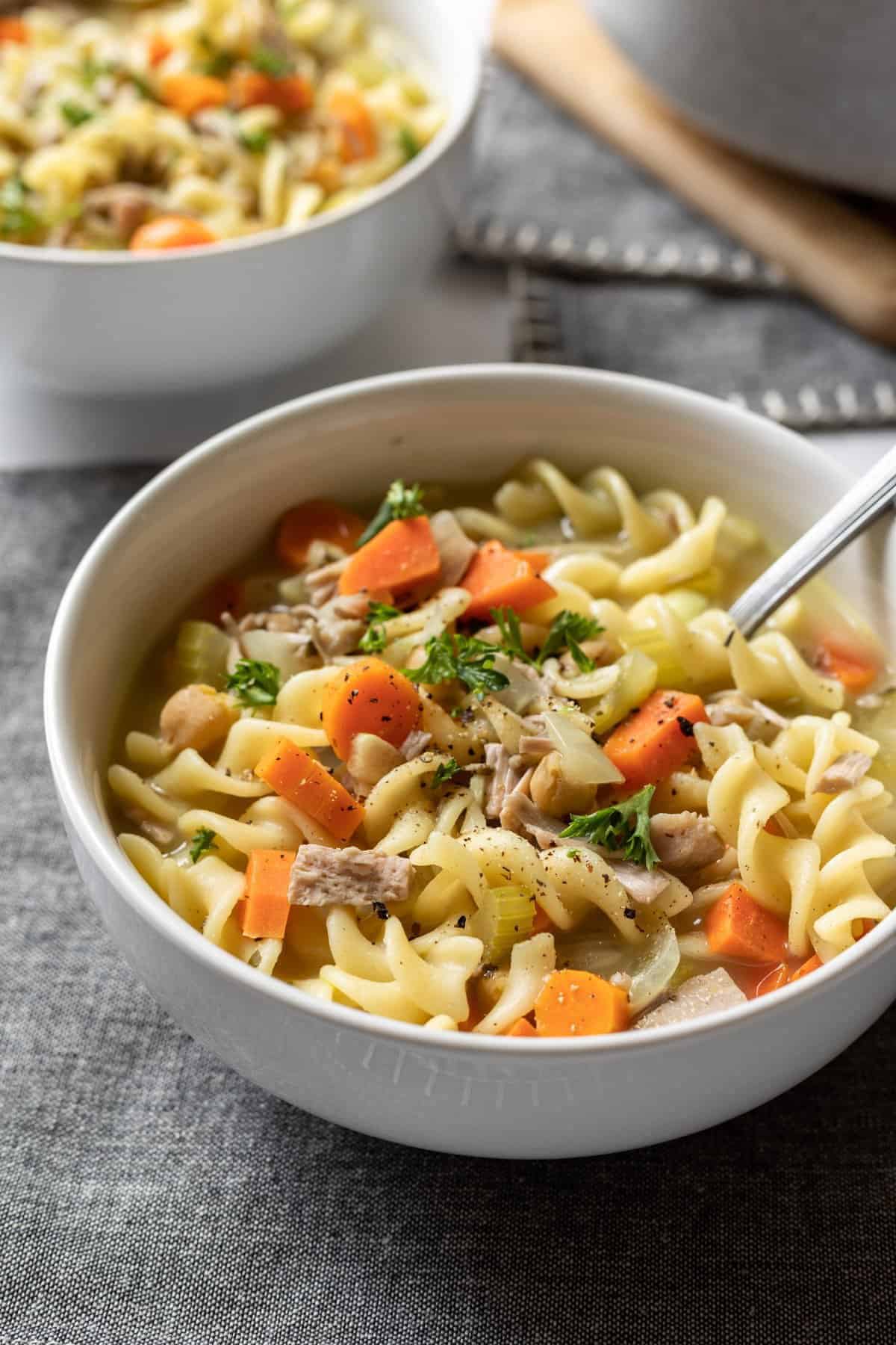 A closeup shot of a bowl of vegan chicken noodle soup on the counter.