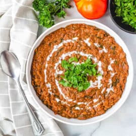 Instant pot dal makhani, served in a white bowl, garnished with cashew cream and fresh herbs.