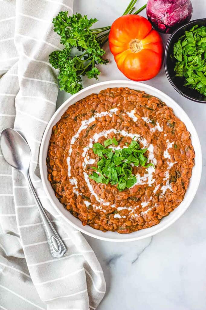 Instant pot dal makhani, served in a white bowl, garnished with cashew cream and fresh herbs.