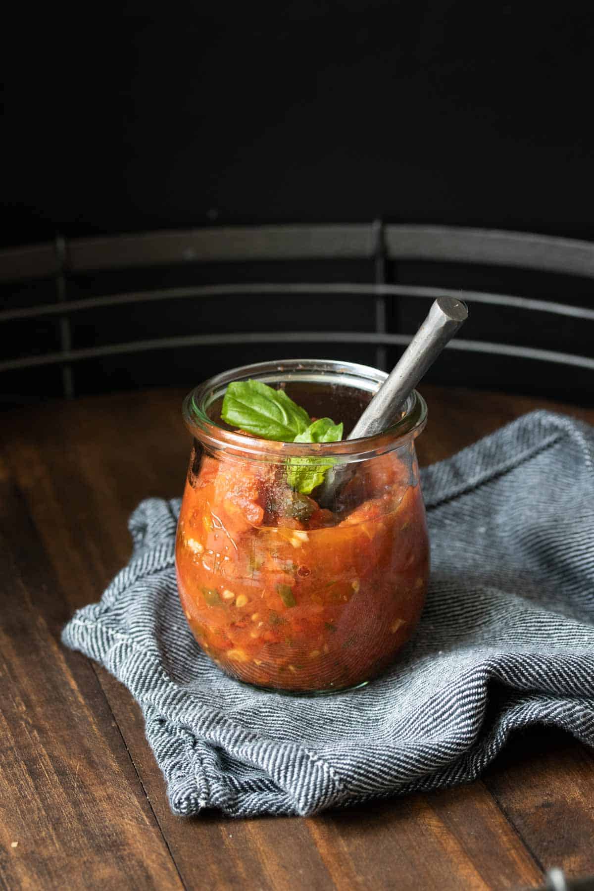 Glass jar with spoon in it filled with red tomato sauce