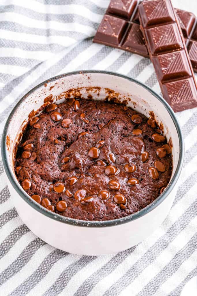 Chocolate vegan mug cake served in a white mug with chocolate chips on top.