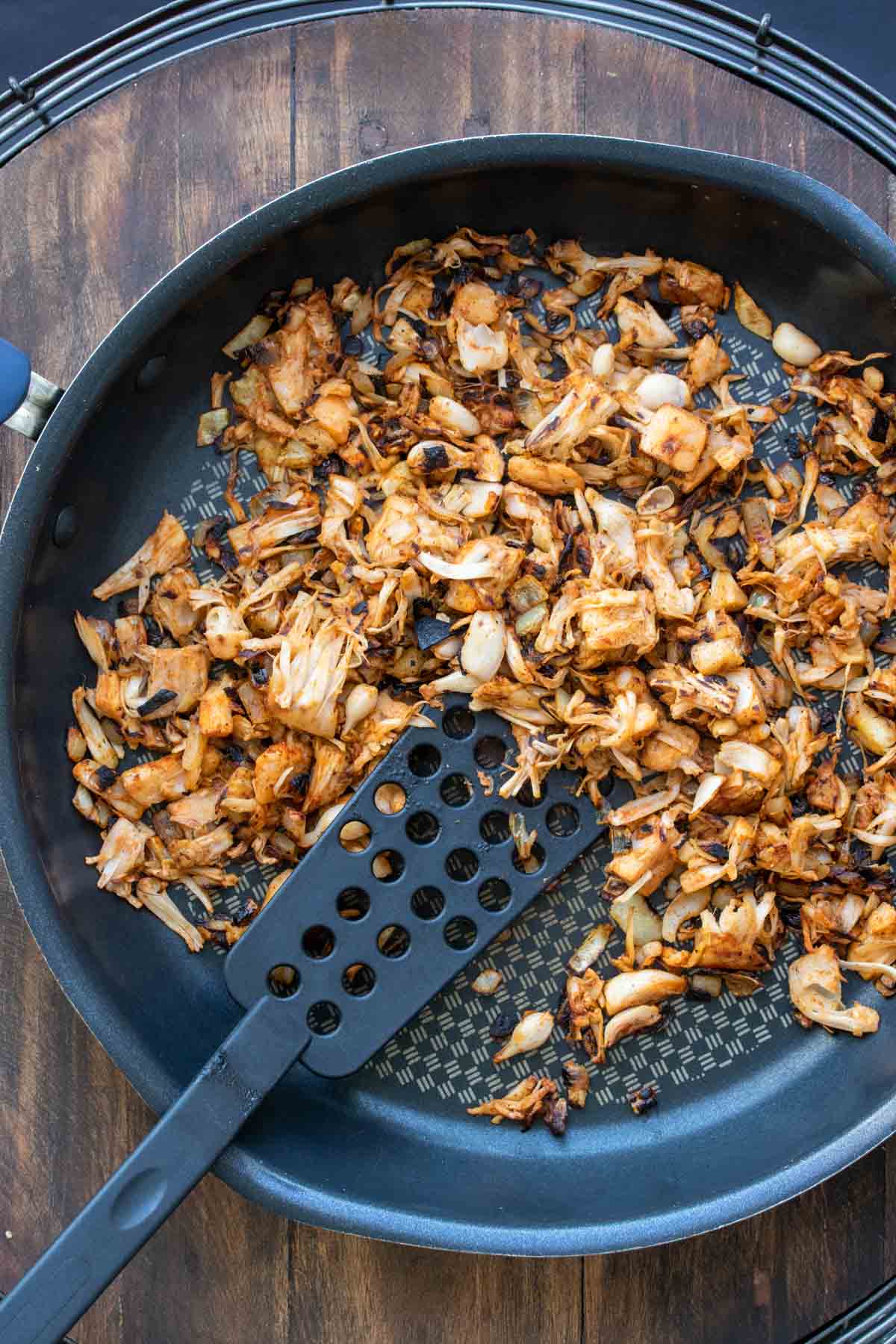 Spatula mixing jackfruit and spices in a pan until browned.