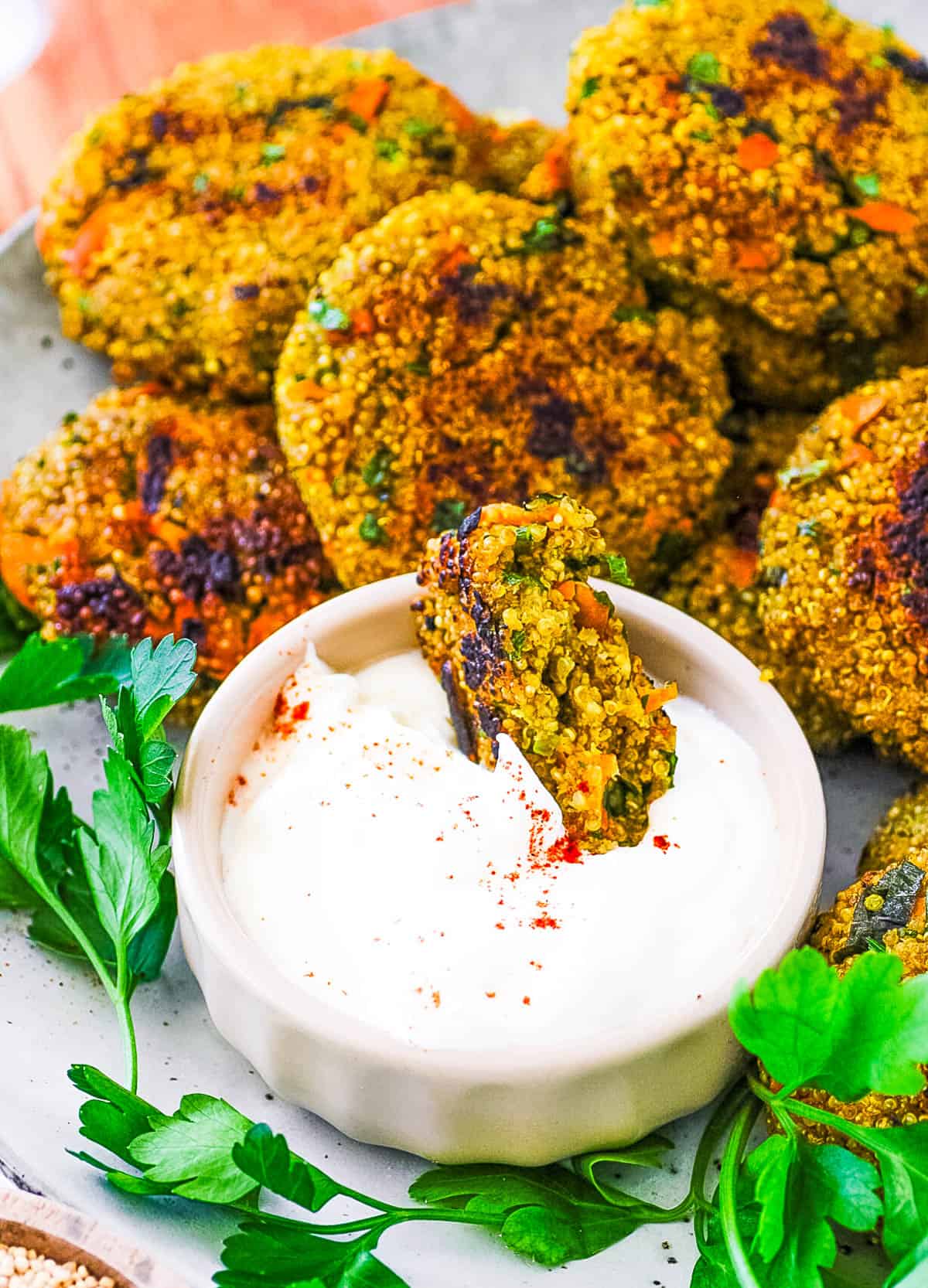 Easy quinoa patties being dipped into dipping sauce.