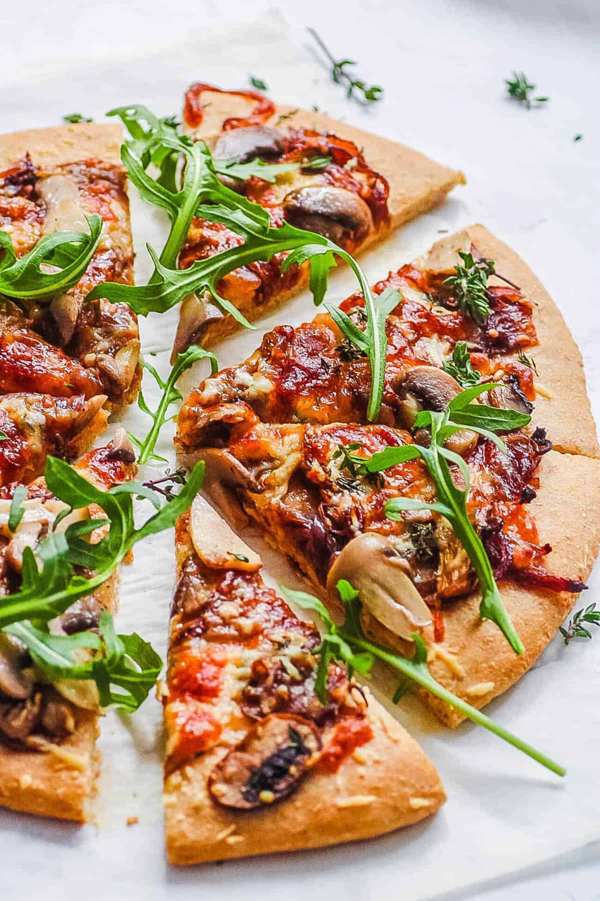 Vegan mushroom pizza served on a white cutting board.