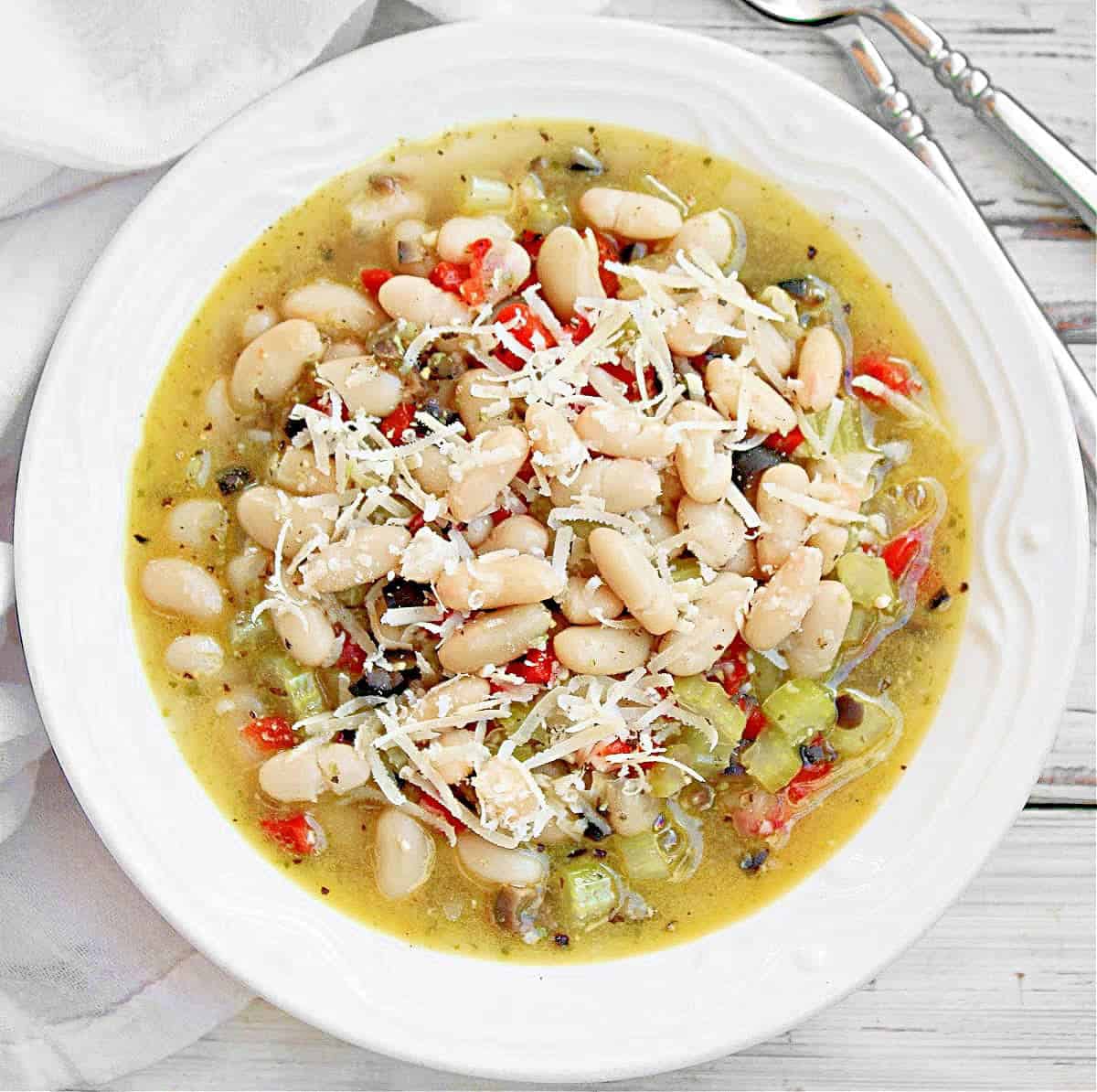 An overhead shot of a white bowl of vegan pesto bean soup.