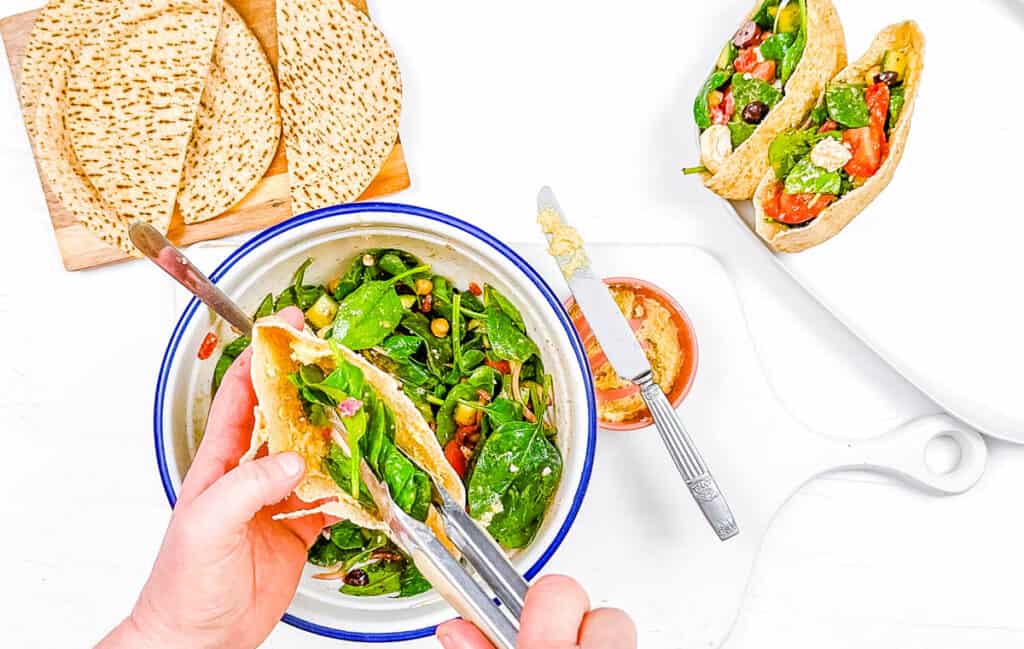 Pita sandwich filling being stuffed into whole wheat pita bread.