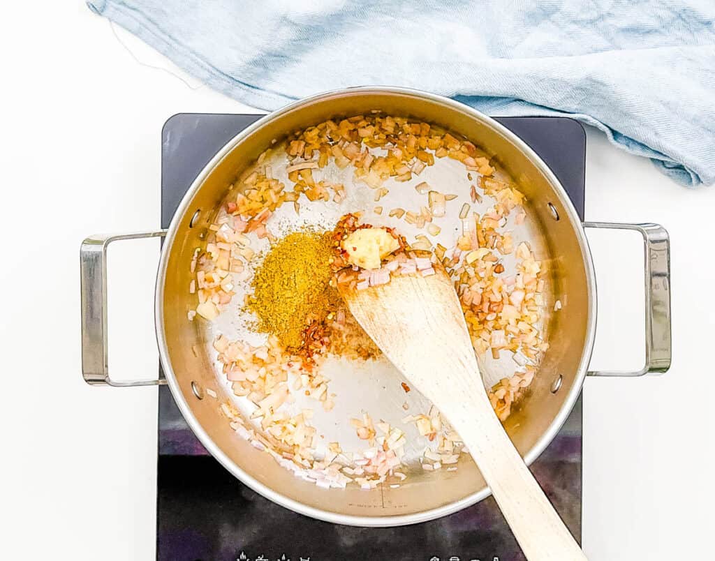 Onions, garlic, and spices sauteeing in a pot on the stove.