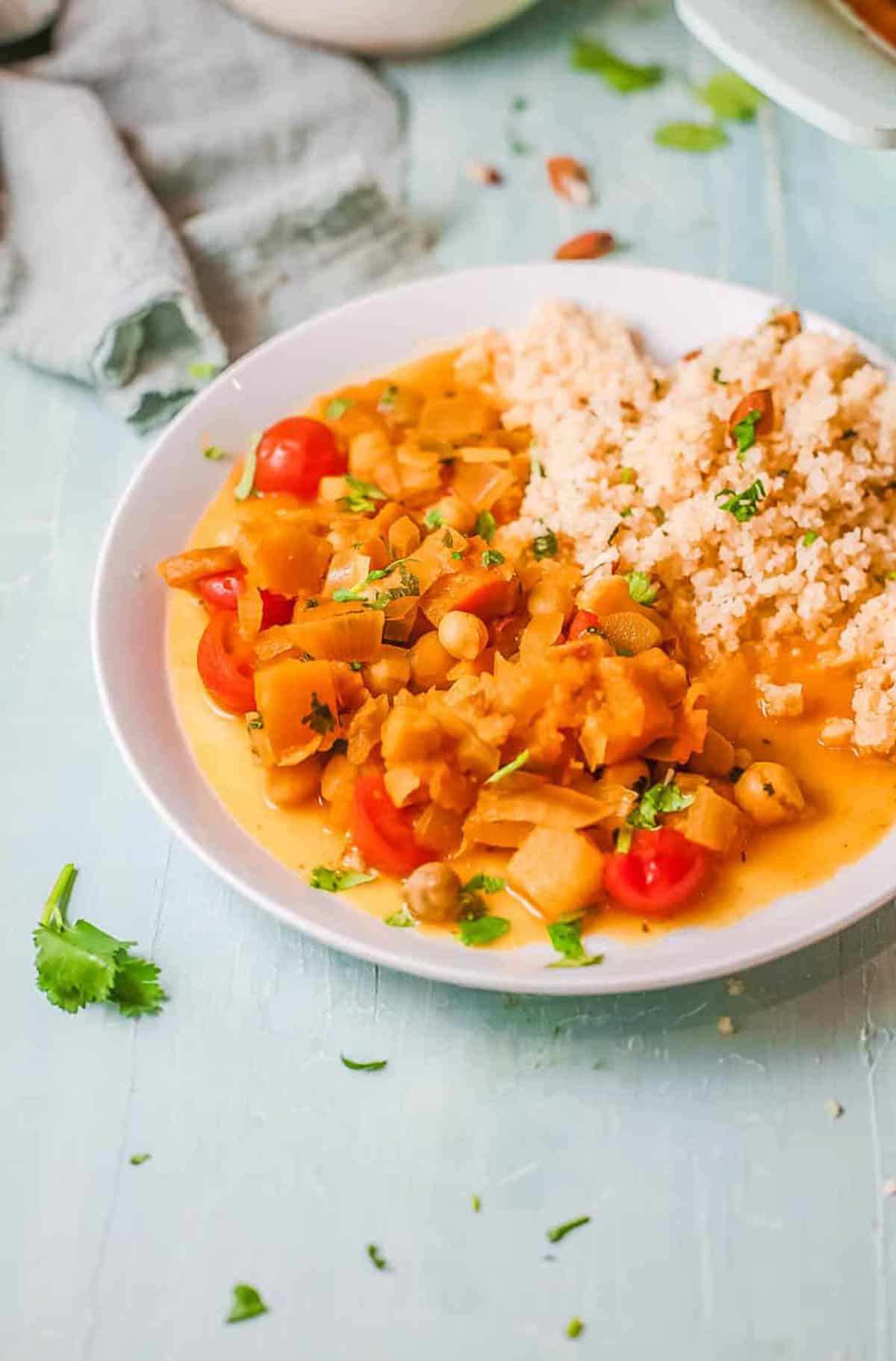 Easy butternut squash and chickpea curry, served on a white plate with couscous on the side.
