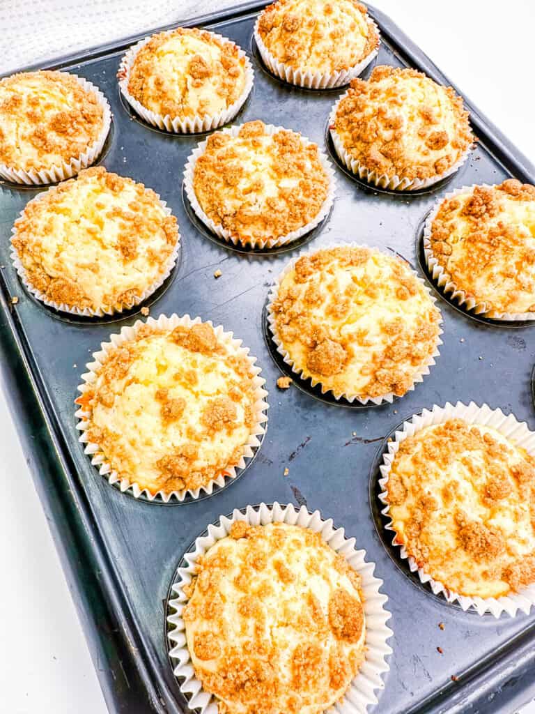 Baked cinnamon muffins with streusel topping in a muffin tin.