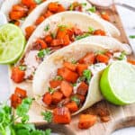 Easy sweet potato tacos with black beans and a spicy yogurt sauce served on a wooden cutting board.