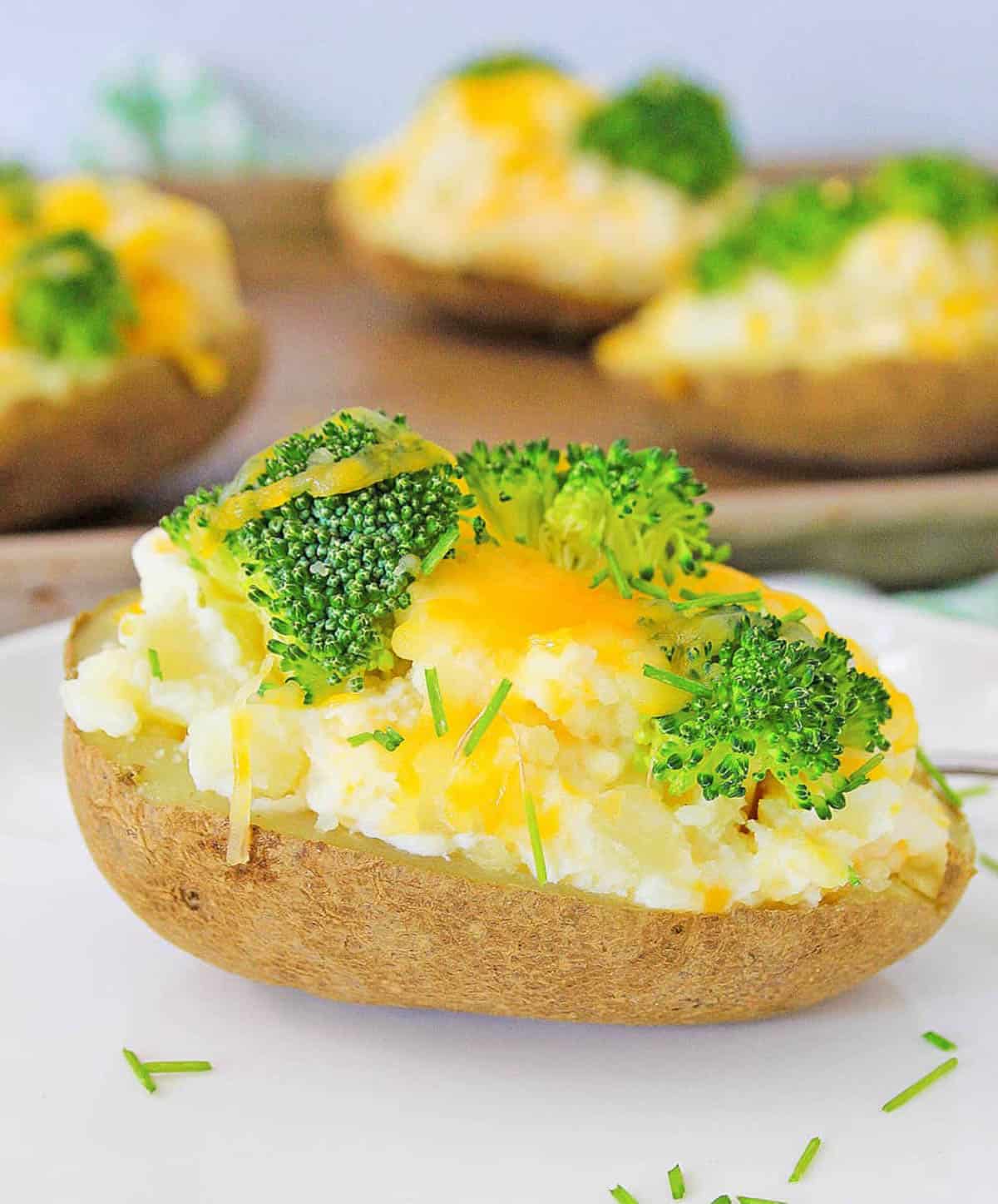 Healthy baked potato topped with broccoli and cheese, served on a white plate.
