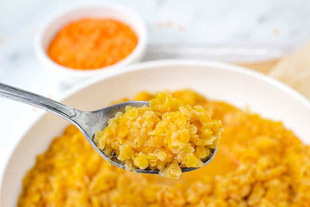 A closeup shot of a scoop of cooked red lentils.