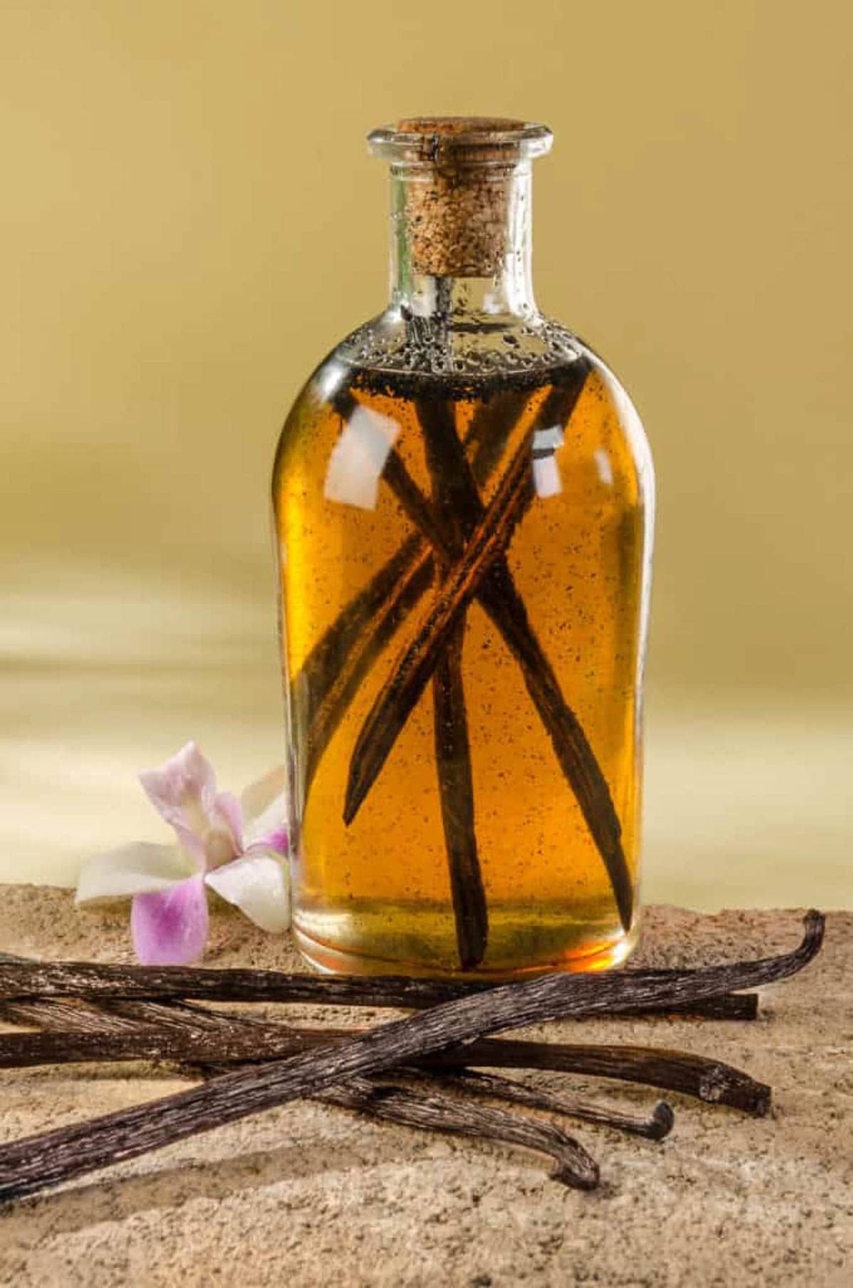 A side shot of a glass bottle of homemade vanilla extract with beans in it.