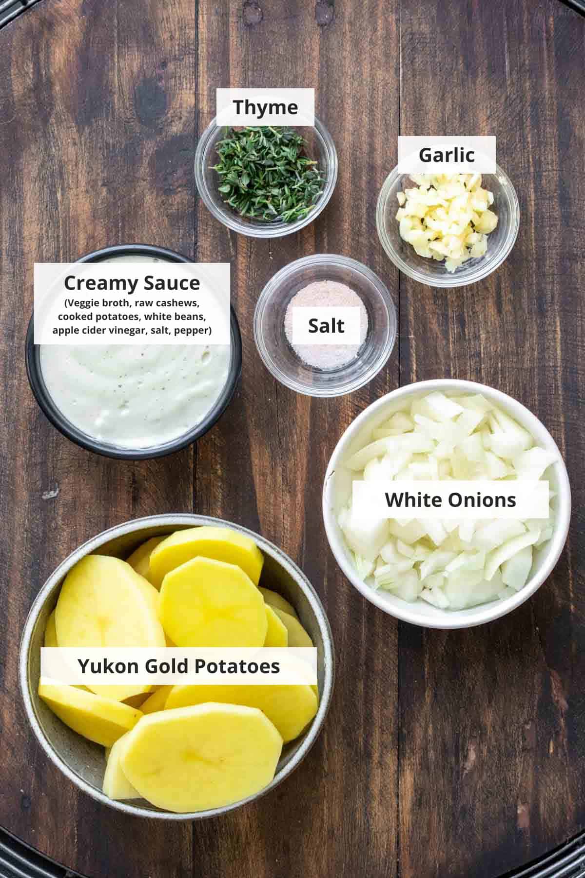 Ingredients for vegan scalloped potatoes on a wood background.