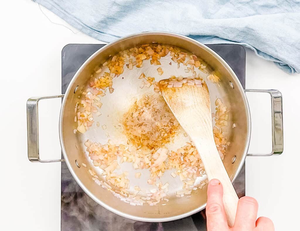 Onions sauteeing in a stock ، on the stove.