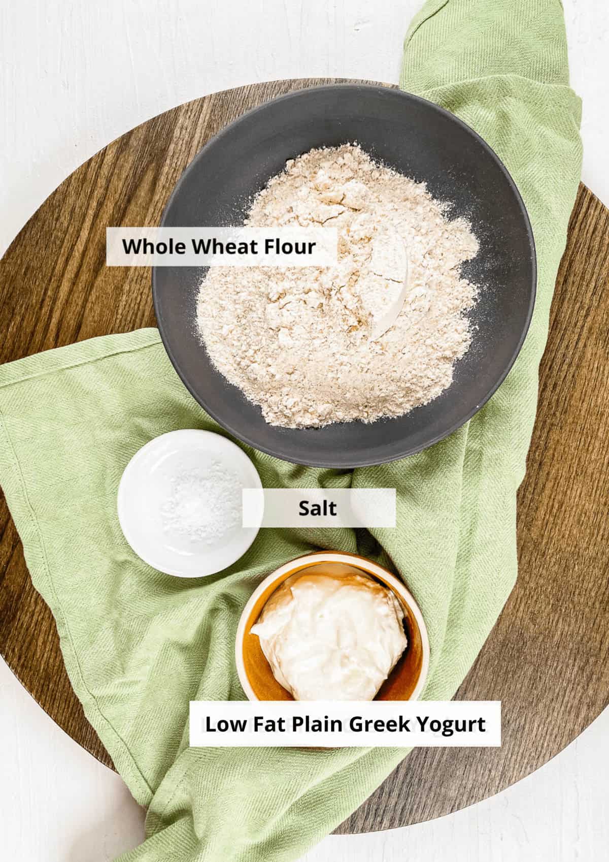 All of the ingredients for low-calorie pizza crust on a wooden cutting board with a napkin.