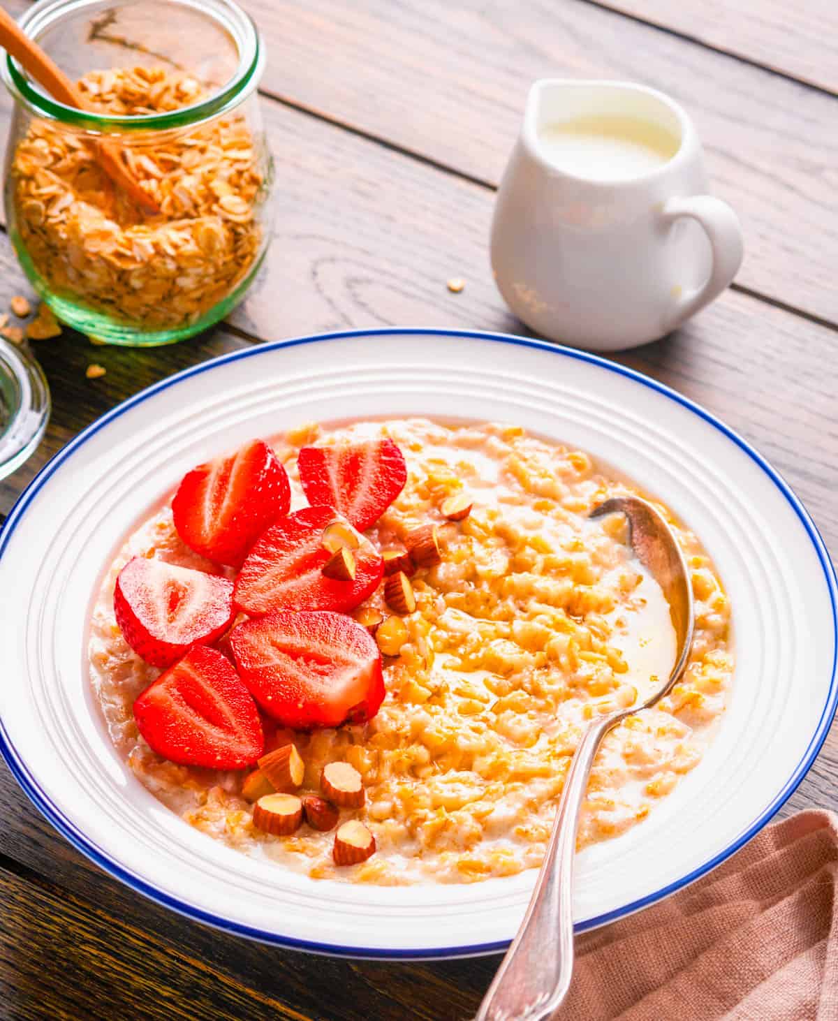 Strawberries and cream oatmeal, served in a white bowl with a spoon.