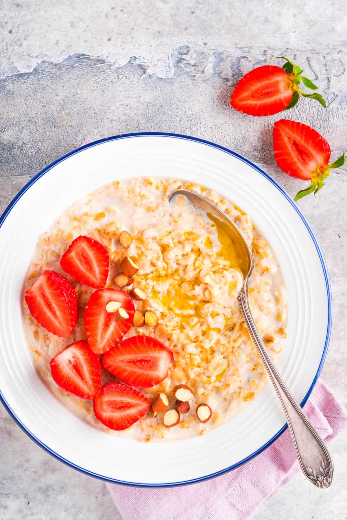 Strawberries and cream oatmeal, served in a white bowl with a s،.