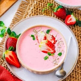 Easy strawberry yogurt served in a peach colored bowl, garnished with fresh strawberries.