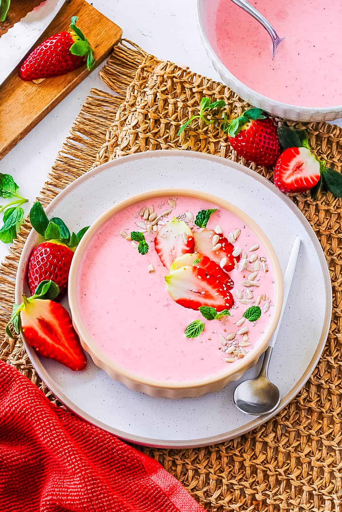 Easy strawberry yogurt served in a peach colored bowl, garnished with fresh strawberries.