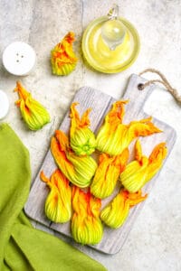 Stuffed zucchini blossoms with ricotta cheese, on a wooden cutting board.