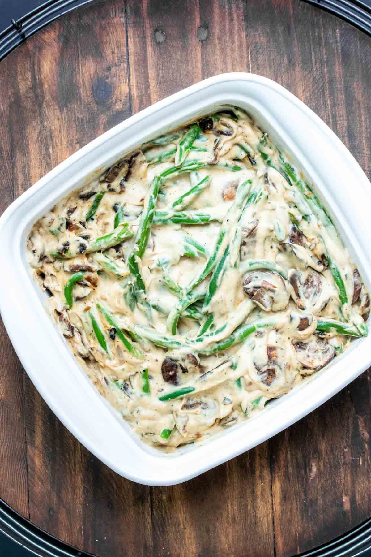 White baking dish filled with green beans and creamy sauce