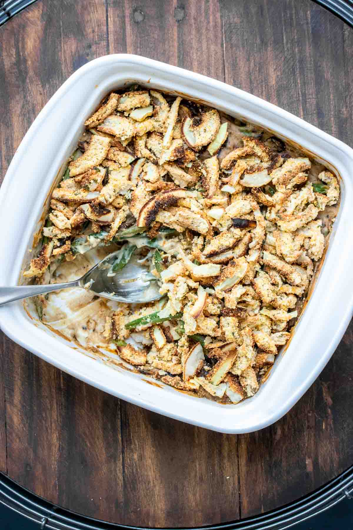 Spoon getting a scoop of green bean casserole out of a white baking dish