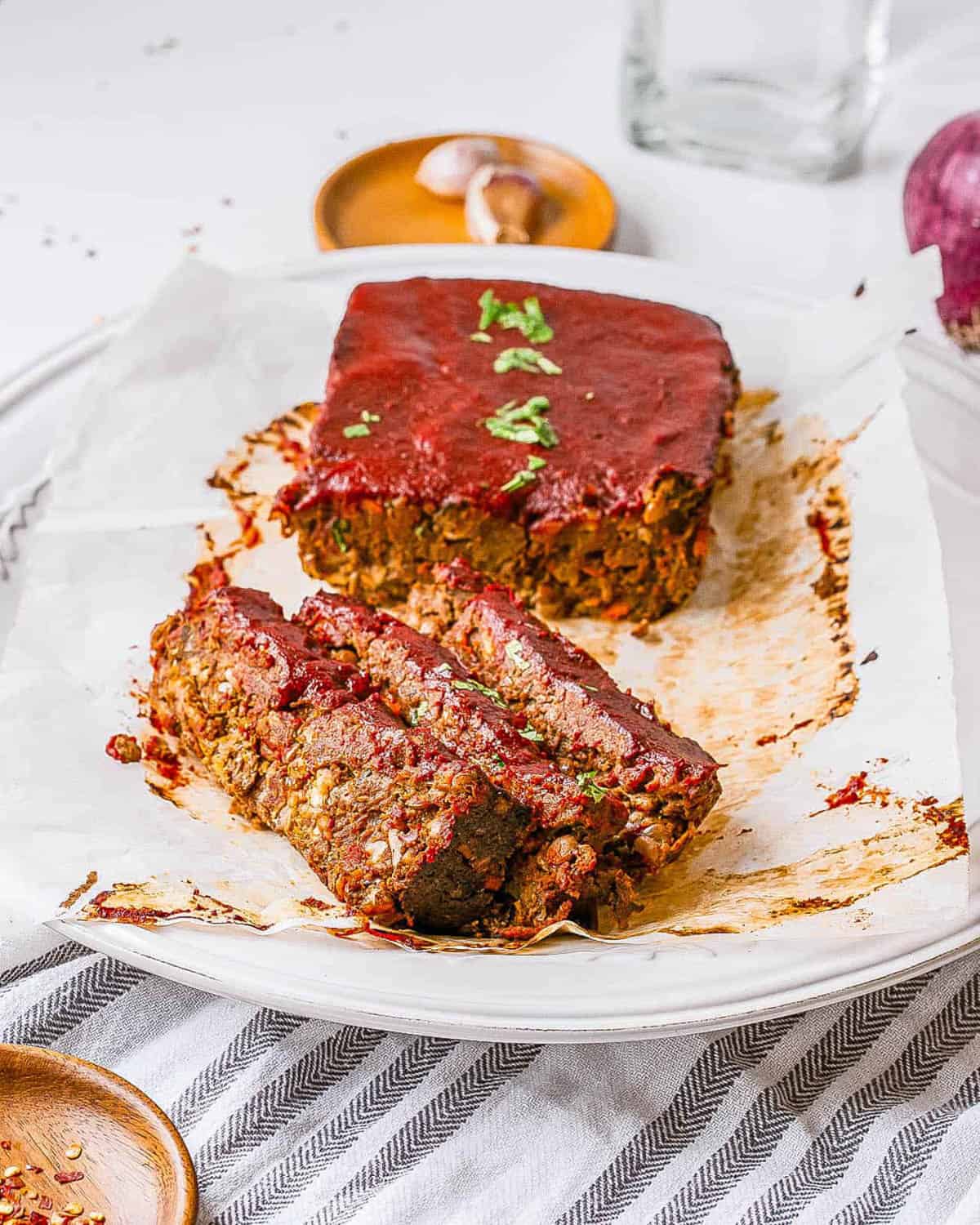 Vegan meatloaf (vegan lentil loaf) with tomato glaze, sliced and served on a white plate.