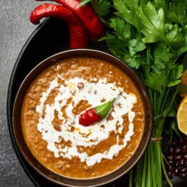 Dal Makhani served in a black bowl with spices on the side.