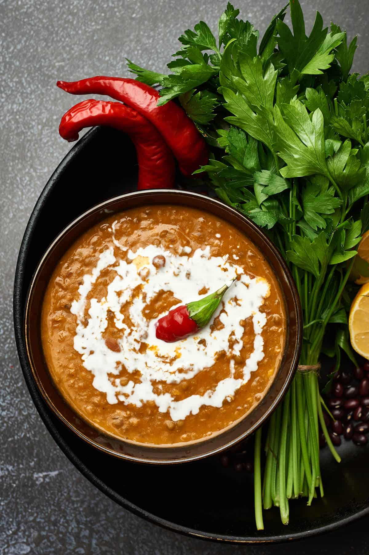 Dal Makhani served in a black bowl with spices on the side.