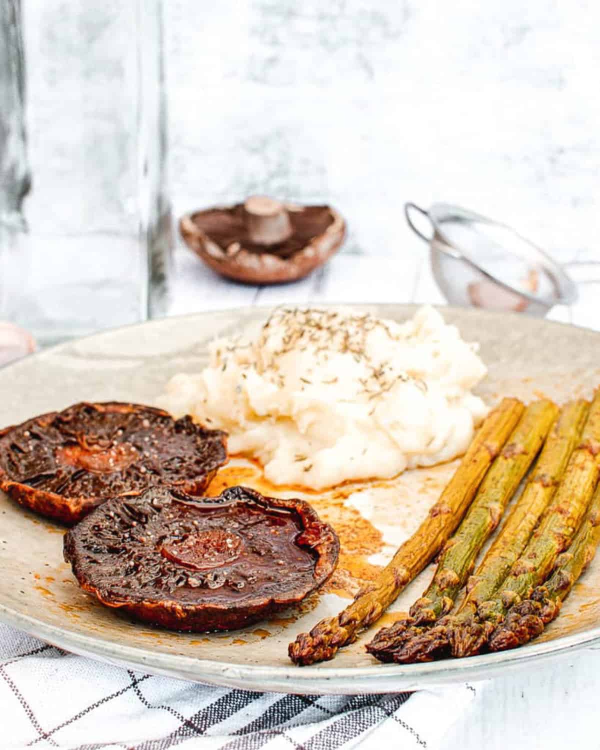 portobello mushroom steaks paired with mashed potatoes and asparagus served on a white plate