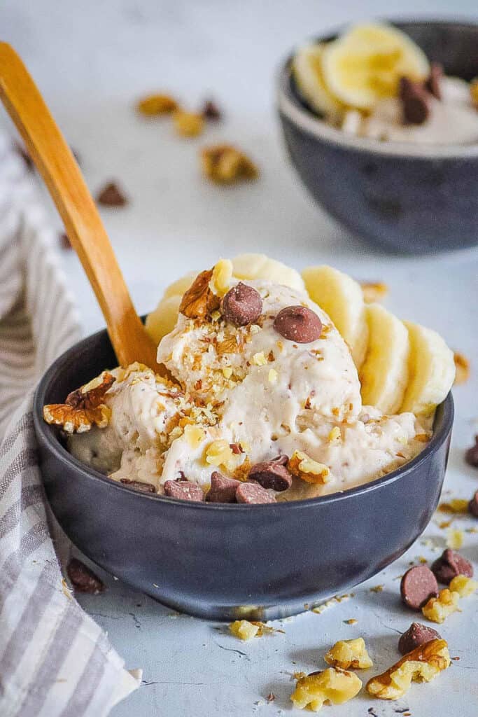Easy chocolate banana ice cream served in a black bowl, topped with chocolate chips and banana slices.
