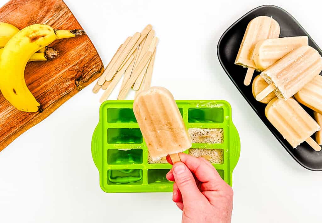 Banana ice pops being removed from popsicle mold.