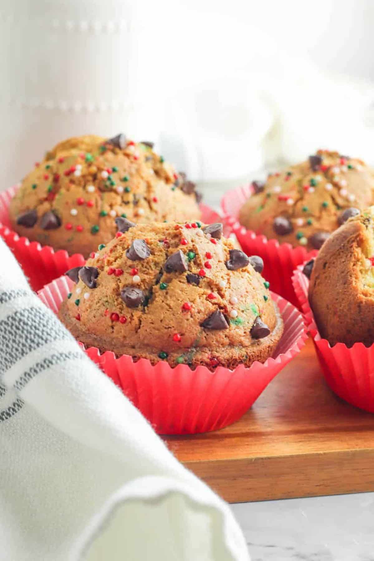 Christmas muffins with chocolate chips on a wooden cutting board.