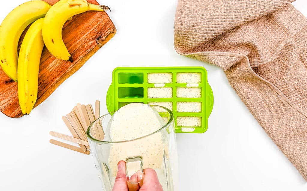 Banana mixture being poured into popsicle molds.