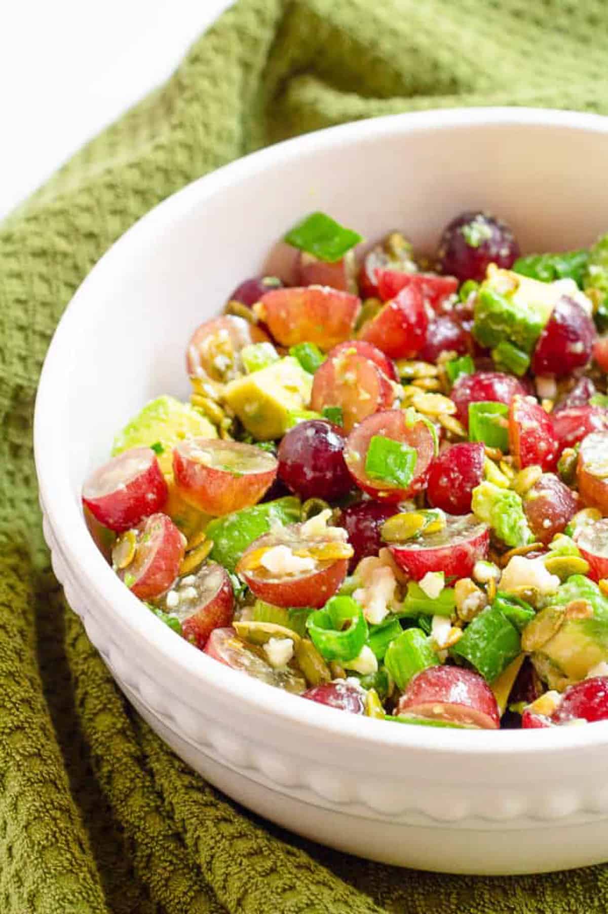 recipe for grape salad with avocado and cotija cheese in a white bowl