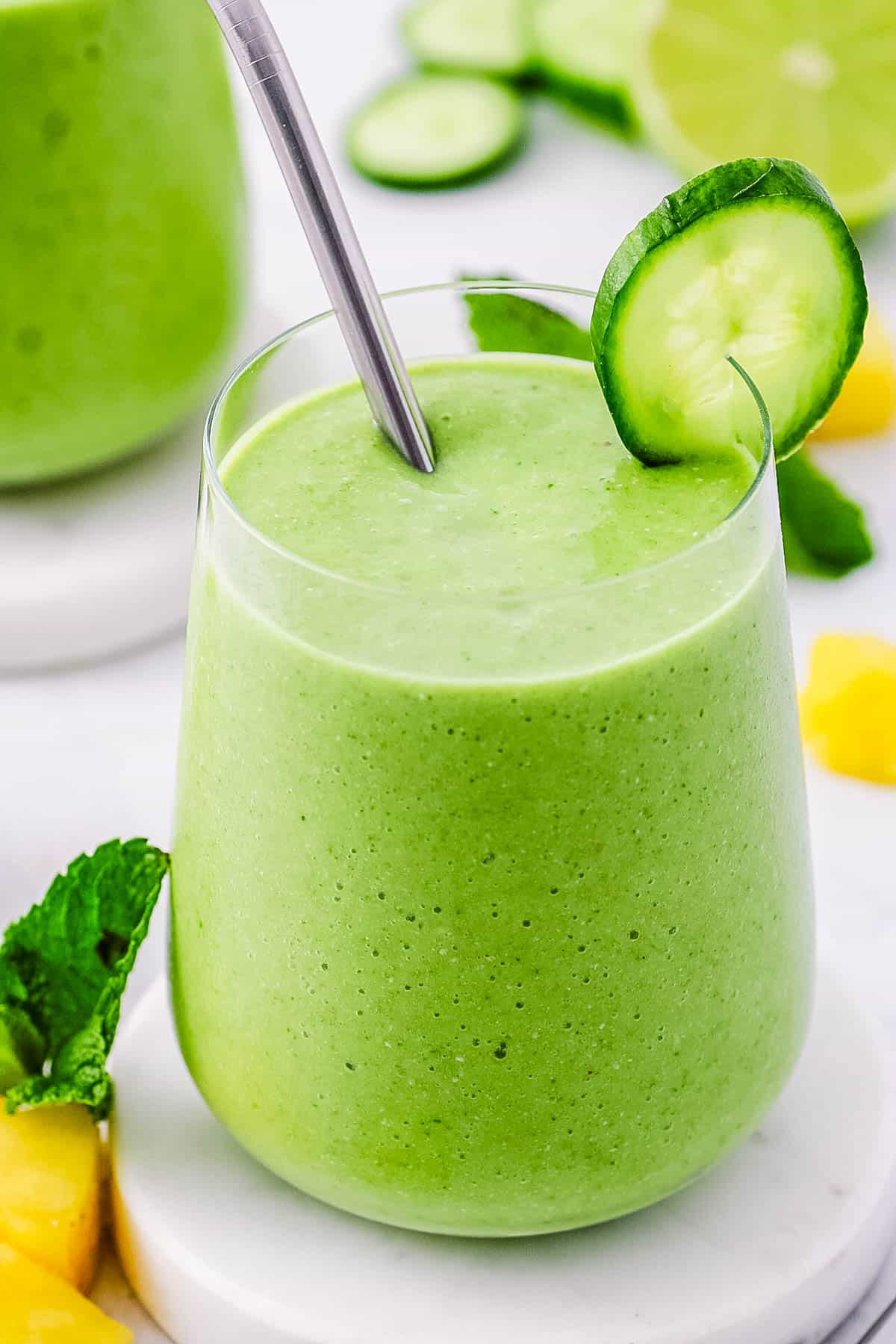 Cucumber pineapple smoothie served in a glass with a straw.