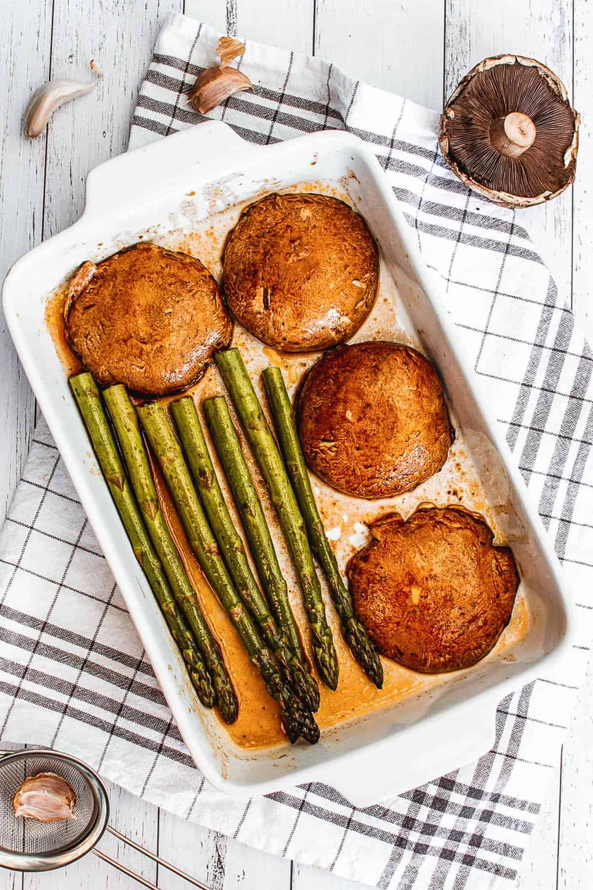 mushrooms and asparagus in a white baking dish, ready to go in the oven