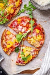 Healthy, easy pita pizza with veggies and cheese as toppings on a cutting board.