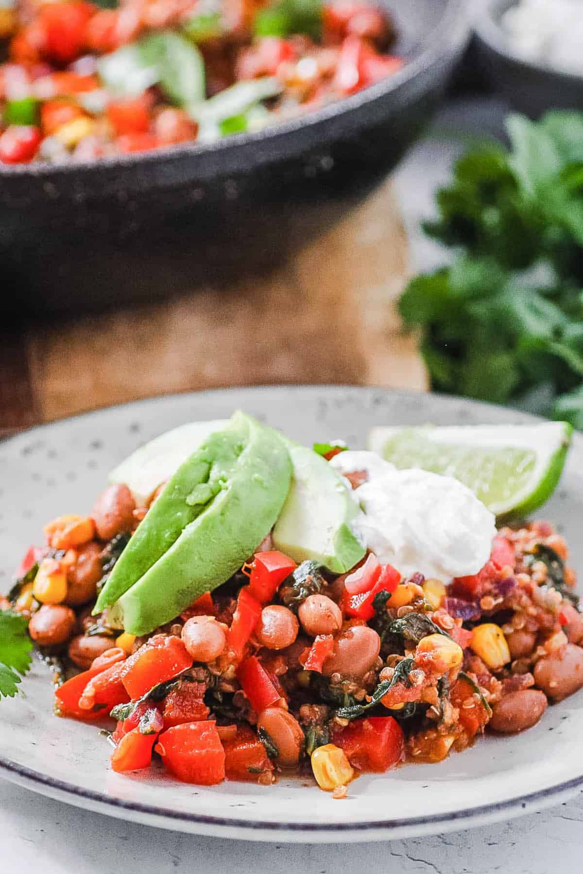 vegan pinto bean casserole on a plate with avocado and lime