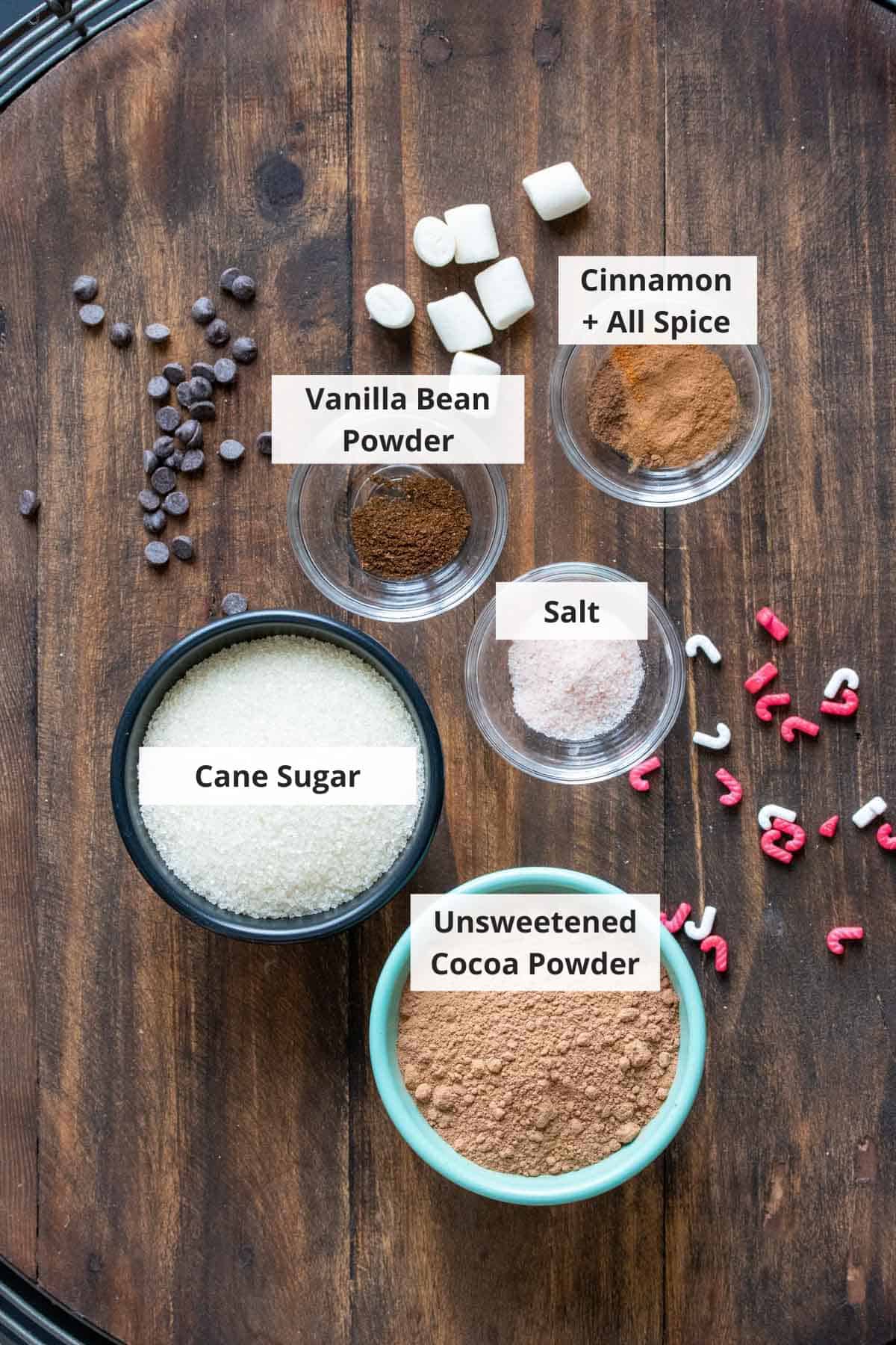 Ingredients for homemade hot chocolate mix recipe on a wood background.