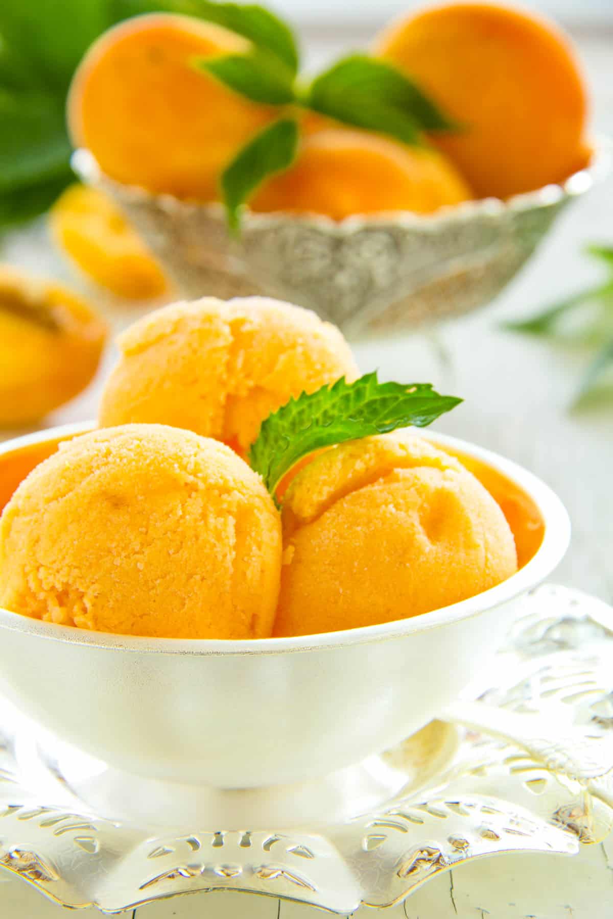 Vegan mango nice cream, served in a white bowl, garnished with mint.