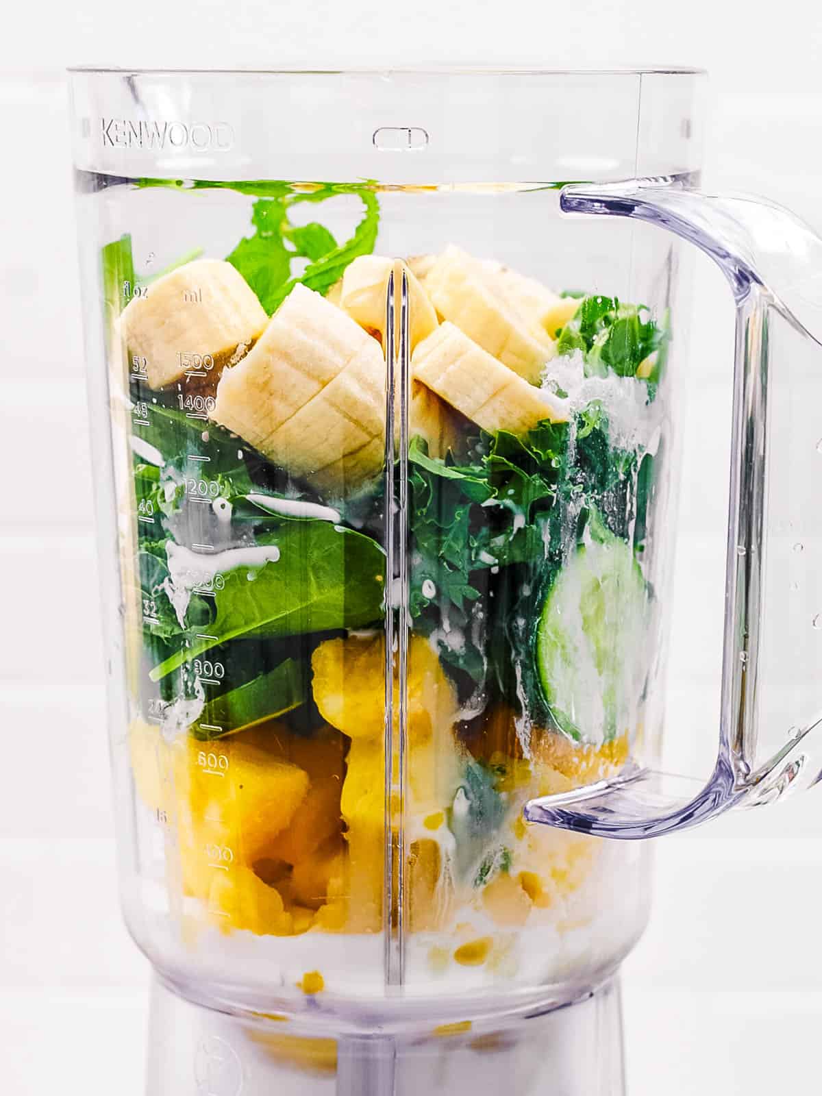 Bananas, spinach, pineapple, cucumber in a blender.